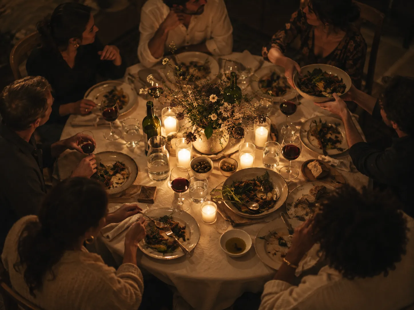 People sharing dinner around a candlelit table, seen from above